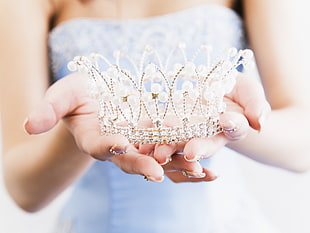person holding silver-colored crown